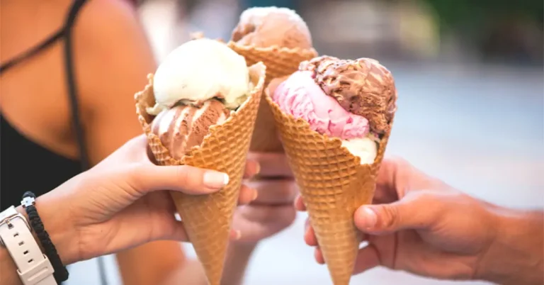 Three large multi-flavoured ice creams being held together by three different people.