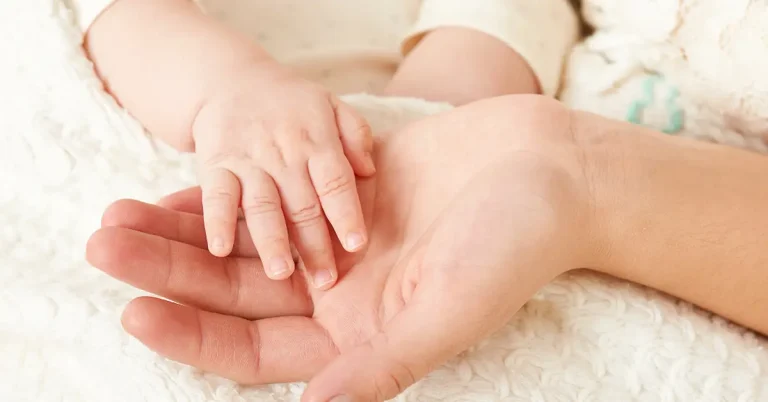 Close up of a young mothers hand with her babies hand.
